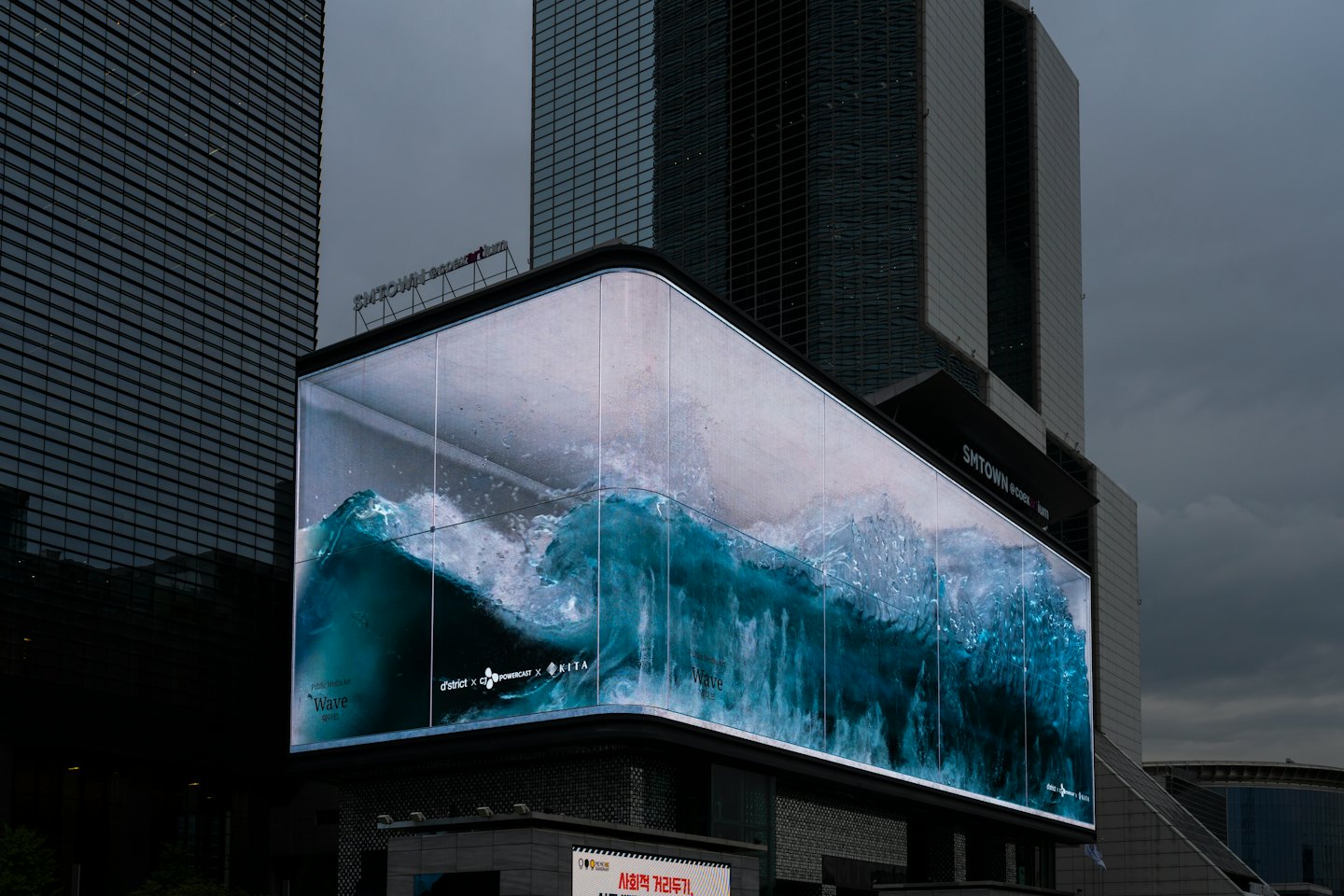 Un grande schermo digitale mostra un'onda verde acqua su un grattacielo.