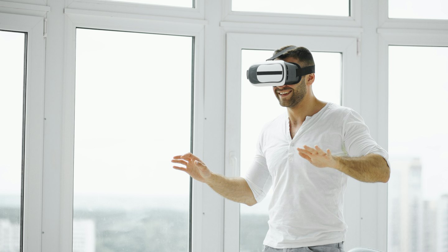 Un uomo con un visore per la realtà virtuale interagisce con un ambiente digitale.