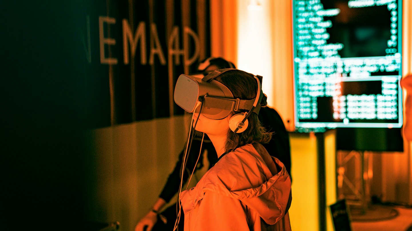 Persona con visore VR e cuffie in una stanza con codice luminoso.